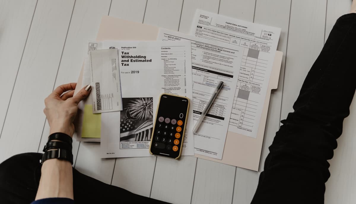 Formularios de impuestos, una calculadora y una pluma sobre un escritorio